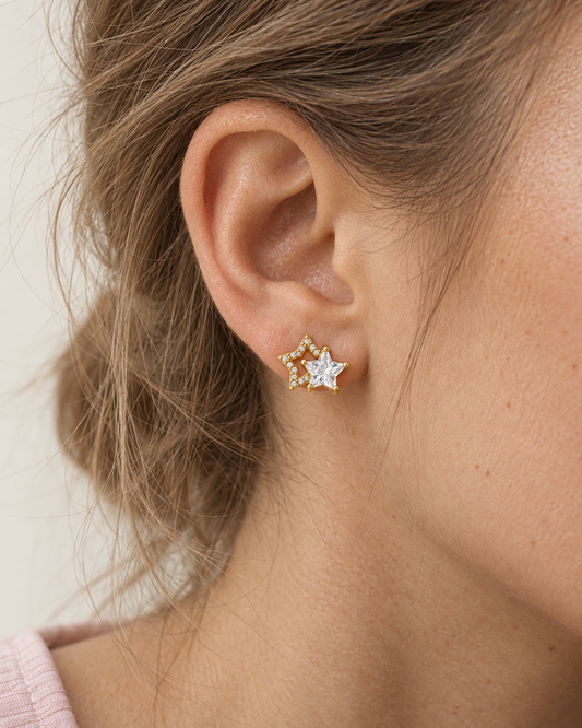 Alice – guldfärgade örhängen med två sammanlänkade stjärnformer och klara, gnistrande detaljer, burna på modell. ISOLDE ACCESSORIES.